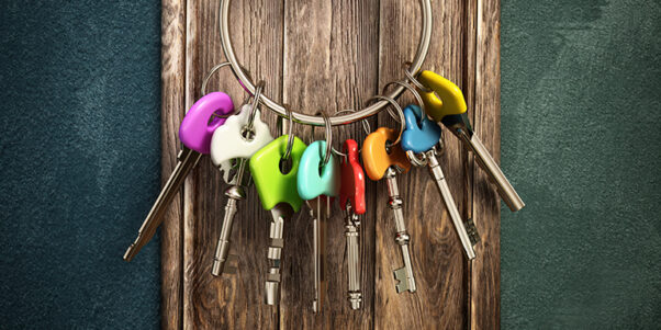 Bunch of keys with various color choices hanging on a wooden wall.