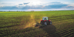 A red tractor cultivating a field at spring