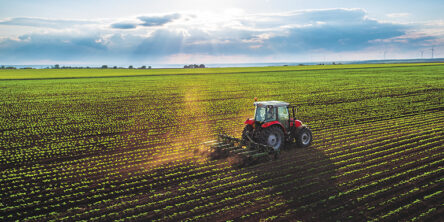 A red tractor cultivating a field at spring